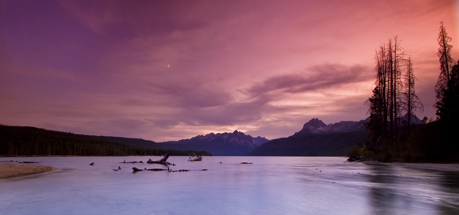 A brilliant pink and purple sunset over periwinkle Redfish Lake. The indego Sawtooth range cuts into the sky.